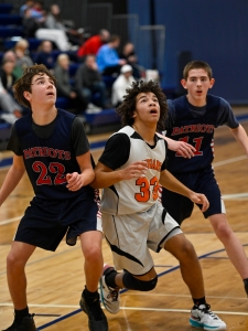 Boys basketball tournament, three boys looking for a rebound