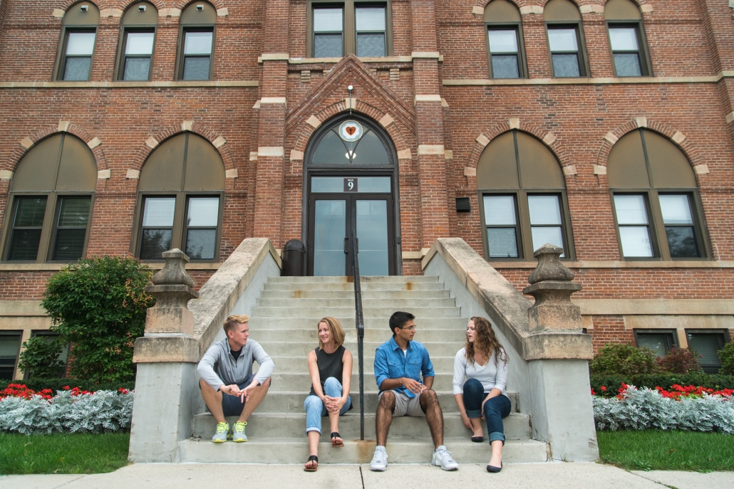 Four students sitting on Old Main stairs